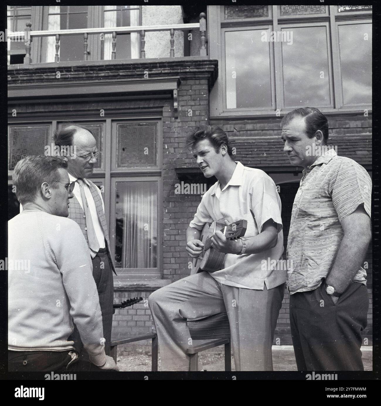 Roger Moore 1958. In der britischen Wohnung, die er mit Dorothy Squires teilte. Von links nach rechts: Schauspieler und Drehbuchautor Digby Wolfe; Roger Moores Vater George Moore, Polizist; Roger Moore; Schauspieler Robert Brown Stockfoto