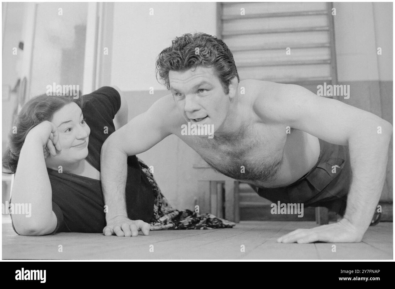 Hattie Jacques und Freddie Mills London 1955. 1955 war Hattie Großbritanniens beliebteste Comedienne und Freddie war Großbritanniens Sportidol. Von 1948 bis 1950 war er Weltmeister im Leichtgewicht und begann eine Karriere im Film- und Fernsehbereich. Hier soll er Hatties persönlicher Trainer sein, aber sie interessiert sich deutlich mehr für seine bauchmuskulatur als für die Übung. Sie könnte es sich leisten, Witze über das Fitnessstudio zu machen. Sie war immer eine sehr große Dame, aber das störte nie ihren riesigen Erfolg auf Bühne, Radio und Leinwand als Comedy-Schauspielerin. Sie war vor allem für ihre Rollen in 14 Filmen bekannt (insbesondere in den Filmen) Stockfoto