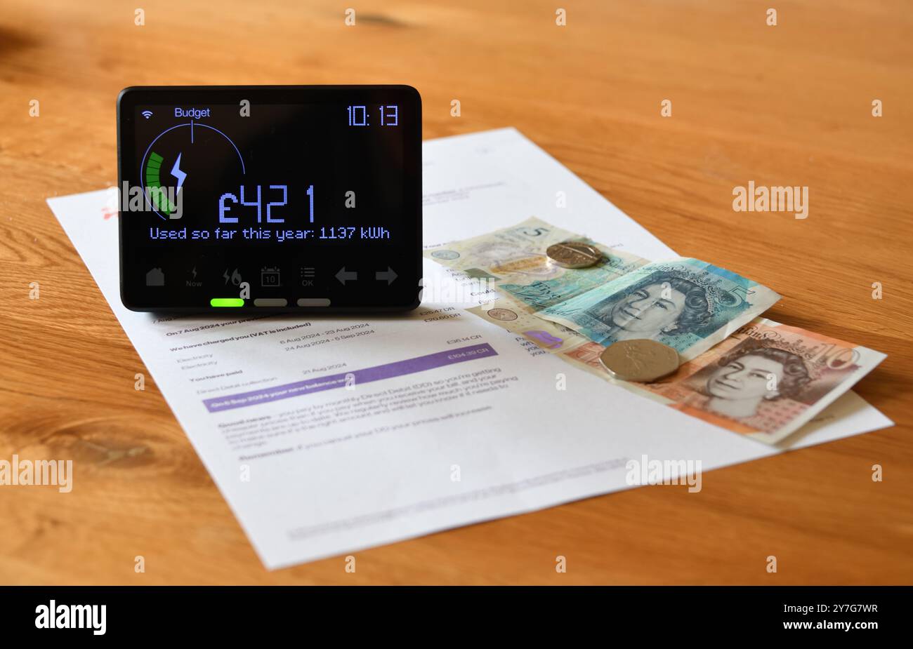 Smart Meter in Home Display (IHD) auf Holztisch, der die bisher in diesem Jahr verbrauchten Kosten in Pfund Sterling und den Energieverbrauch in Kilowattstunden anzeigt Stockfoto