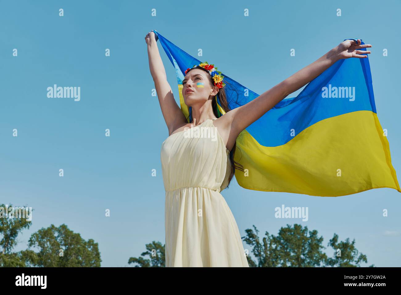 Schöne ukrainische Frau mit Nationalflagge mit Himmel im Hintergrund Stockfoto