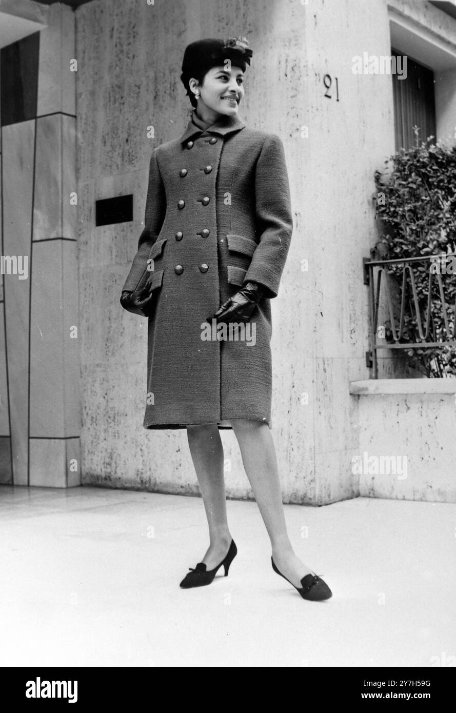 Paris : typisch für die zurückhaltende Eleganz der aktuellen Kollektion von Yves Saint Laurent ist dieser rote Mantel . Der Stoff ist eine harte Wolle in Currybraun. Beachten Sie den doppelten Verschluss und die doppelten Pattentaschen auf beiden Seiten . Der Mantel ist mit beigefarbenem Wolletamin gefüttert und passt zu dem schlichten ärmellosen Kleid darunter, das ein zweiteiliges Kleid simuliert. Hut aus braunem Filz als Kontrastmittel. 14. August 1964 Stockfoto