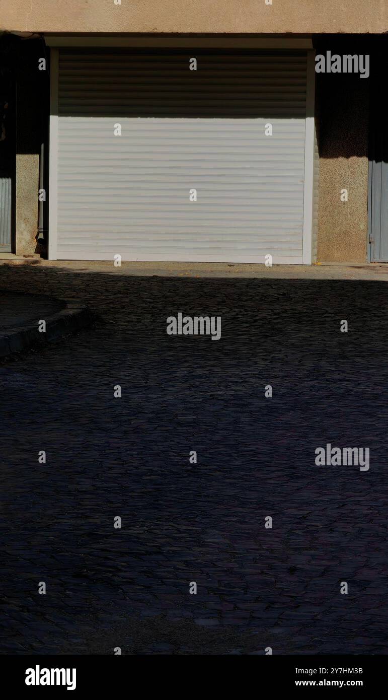 Geschlossener Garagentorrahmen mit Kopfsteinpflasteroberfläche – urbaner Minimalismus Stockfoto Geschlossener Garagentorrahmen mit Kopfsteinpflasteroberfläche – urbaner Minimalismus Stockfoto