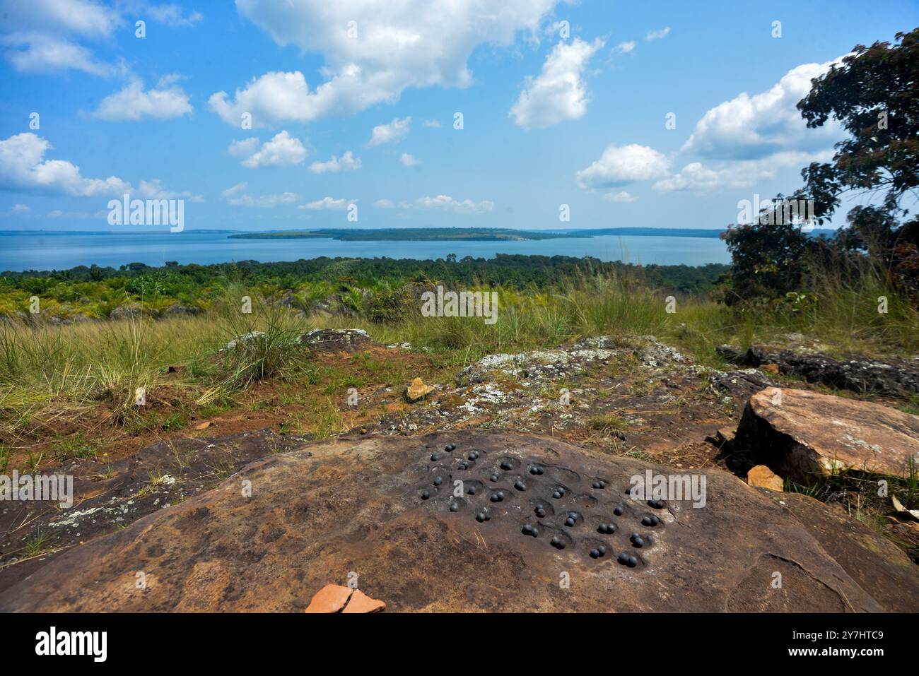Männer, die Local Draft ( Mweso) spielen, deren Spielbrett auf einem Felsen im Ssese Island Lake Victoria Uganda gekrümmt ist Stockfoto