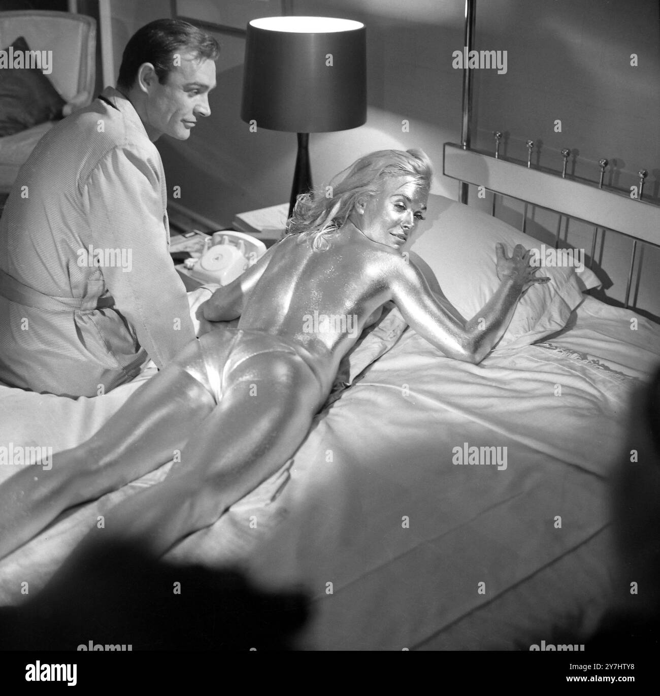 20. APRIL 1964 SEAN CONNERY MIT SHIRLEY EATON, DER VON KOPF BIS FUSS MIT GOLDFARBE BESPRÜHT WIRD, FÜR EINE SZENE IM NEUESTEN JAMES BOND-FILM „GOLDFINGER“. PINEWOOD STUDIOS, LONDON, ENGLAND. Stockfoto