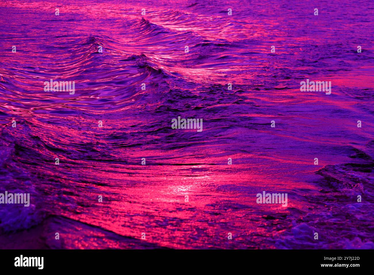 Oberflächenstruktur des Wassers gegen die Reflexionen des violetten Sonnenuntergangs auf der Adria in Montenegro, violetter abstrakter Hintergrund Stockfoto