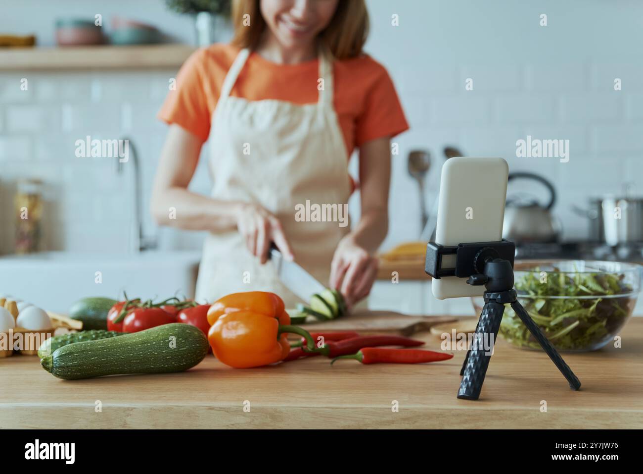 Junge Frau kocht und vloggt, während sie in der Hausküche steht Stockfoto