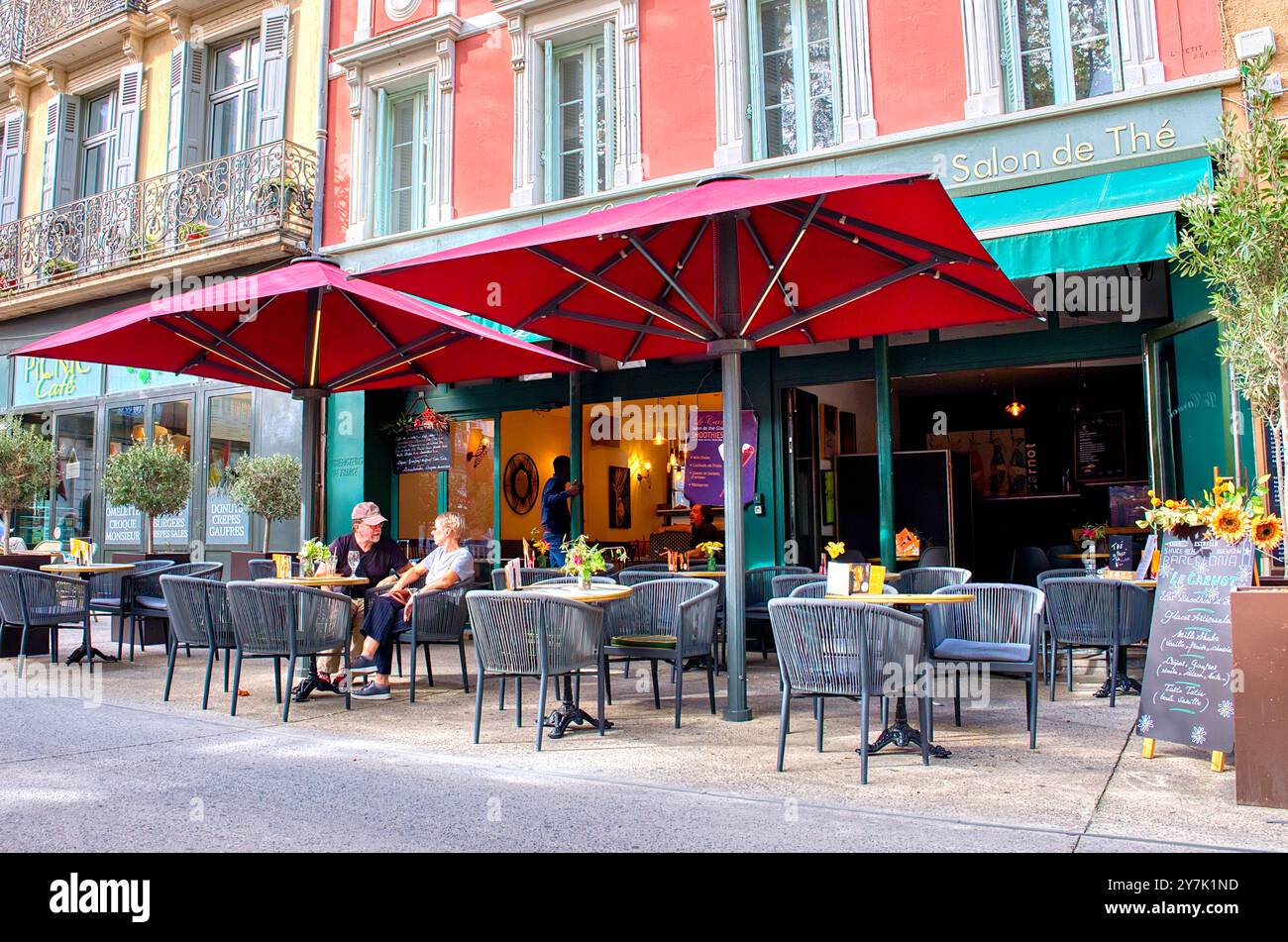 Carcassonne Aude France 09.30.24 Cafe ohne seitliche Korbstühle und Eisentische. Zwei Senioren sitzen hell verzierte Gebäudefassade. Fenster mit Blende, Stockfoto