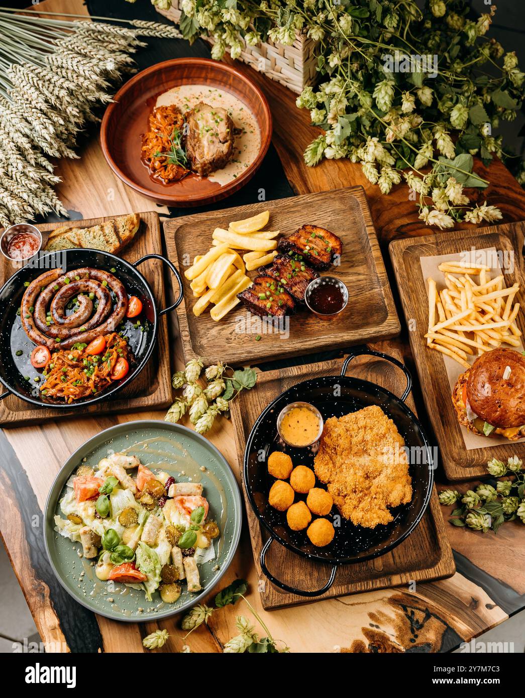 Blick von oben auf verschiedene Gourmetgerichte mit Wurst, Schweinerippchen, Salat, Schnitzel und Burger mit Pommes frites Stockfoto