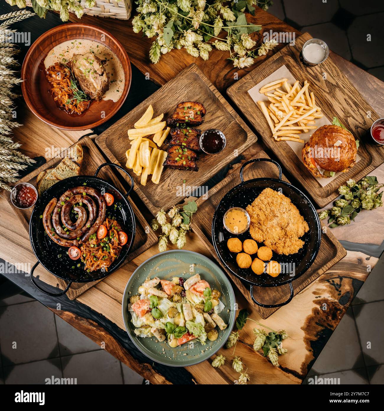 Blick von oben auf verschiedene Gourmetgerichte mit Wurst, Schweinerippchen, Salat, Schnitzel und Burger mit Pommes frites Stockfoto