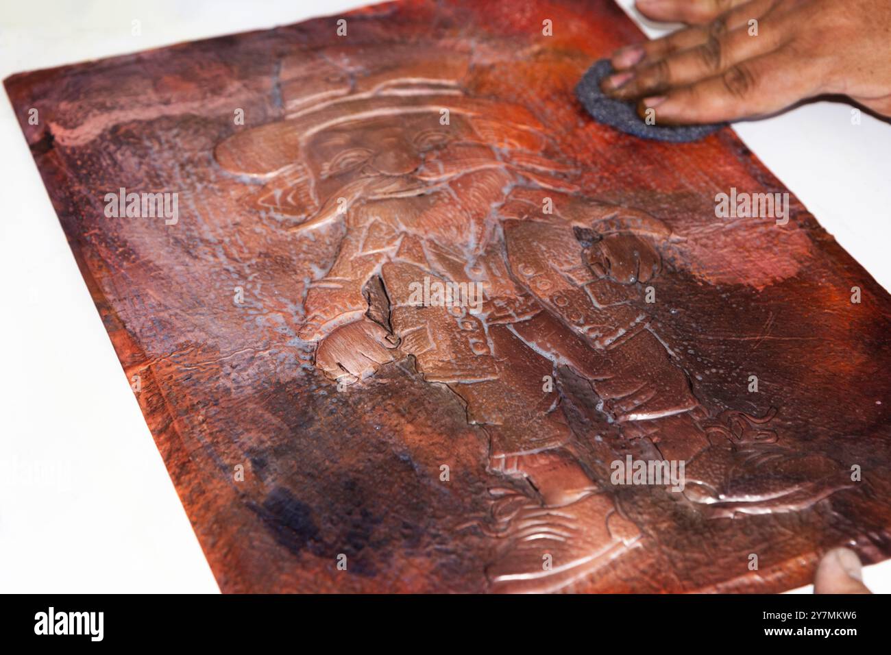 Nahaufnahme von Handwerkern, die ein Kupferblech vorsichtig mit einem Tuch abwischen und für den Poliervorgang vorbereiten Stockfoto