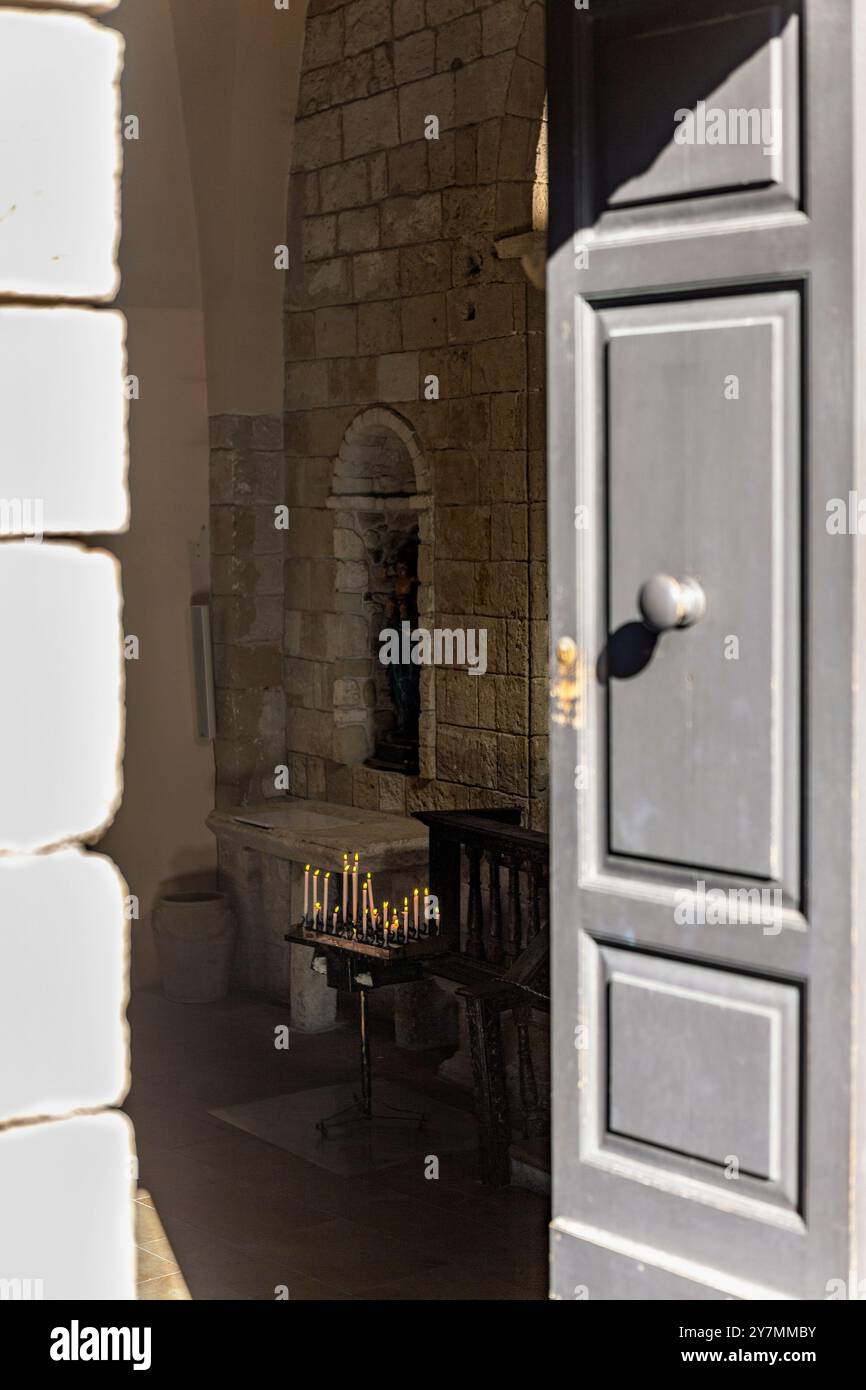 Offene Tür führt in das Innere mit beleuchteten Kerzen, Castelsardo, Sardinien Stockfoto