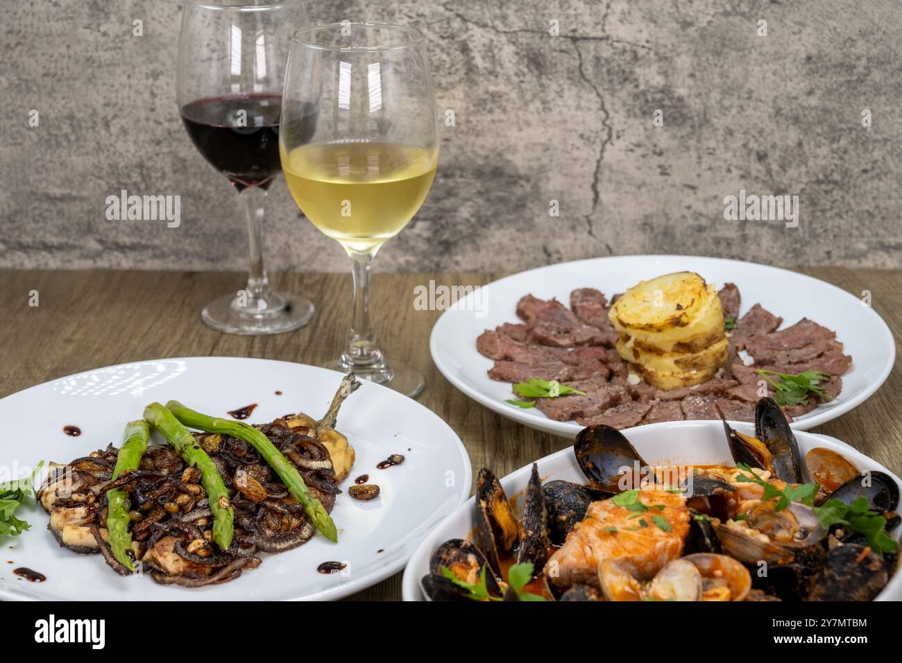 Italienische Küche mit Rot- und Weißwein, dünnem New Yorker Steak, Forelle mit Spargel und einer Schüssel mit Meeresfrüchten. Stockfoto