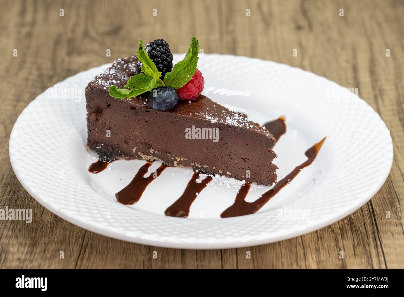 Scheibe bittersüßer Schokoladenkuchen mit Fruchtgarnitur und Schokoladengarnitur zum Nachtisch. Stockfoto
