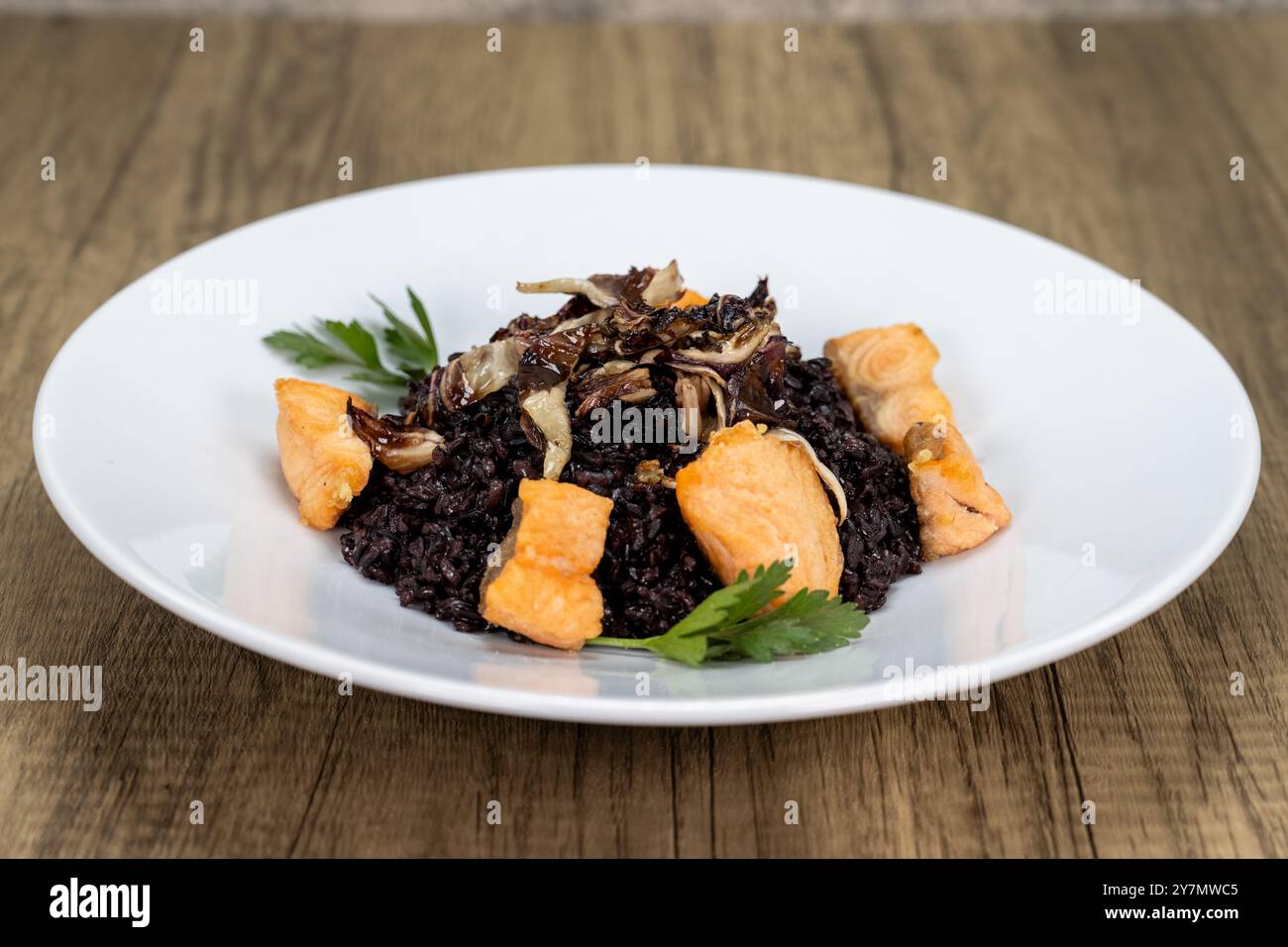 Bissgroßer Lachs auf einem Bett aus schwarzem Reis serviert und perfekt gekocht. Stockfoto