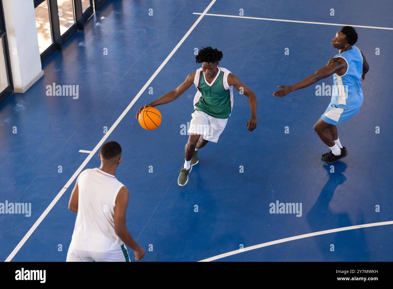 Basketball spielen, drei afroamerikanische Männer in Aktion auf dem Hallenplatz, Dribbeln und Verteidigen Stockfoto