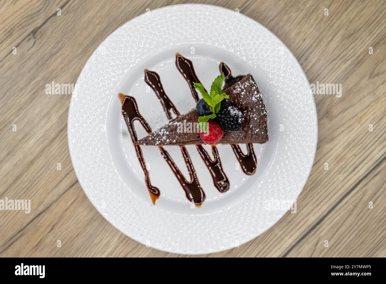 Blick von oben auf ein Stück bittersüßen Schokoladenkuchen mit Fruchtgarnitur und Schokoladengarnitur zum Nachtisch. Stockfoto