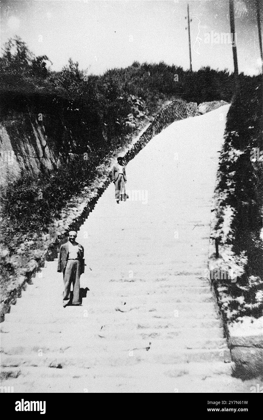 Zwei Überlebende posieren auf dem Stein „Todesstiege“ im Mauthausen Wiener Graben. Mauthausen war ein NS-Zwangsarbeitslager, das Teil des Mauthausen-Komplexes war. Auf seiner Höhe hatte sie 85.000 Gefangene auf einmal. Es war berüchtigt für seine Härte - es wird geschätzt, dass von den 190.000 Gefangenen, die während der Operationen dort festgehalten wurden, die Hälfte vollständig gestorben ist. Dort befand sich der Wiener Graben und seine gefürchteten Todessteige, wo viele starben, als sie riesige Lasten die 186 Steintreppen hinauftrugen. Stockfoto