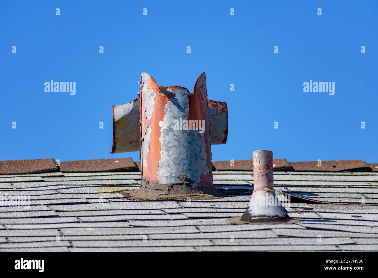 Eine alte, verrostete Dachlüftungsleitung mit abgesplitterter Farbe, die Anzeichen von Verfall zeigt und reparaturbedürftig ist. Stockfoto