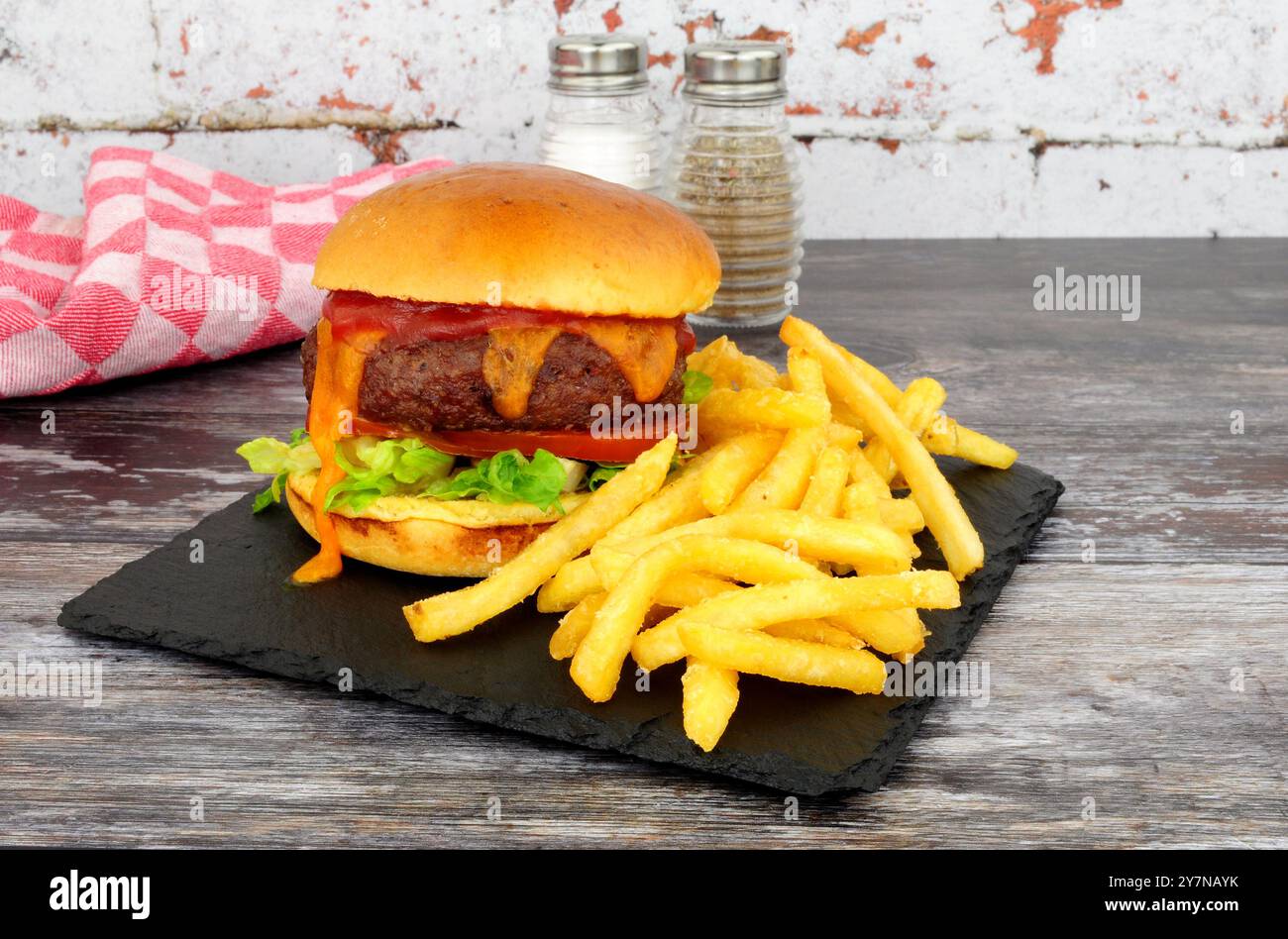 Ein Viertel Pfund Käse Burger und Pommes frites in einem Brioche Brötchen mit Salat, Tomaten und roter Sauce Stockfoto