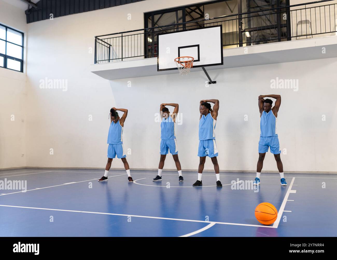 Basketballspieler dehnen sich auf dem Platz aus und bereiten sich auf das Training drinnen vor Stockfoto