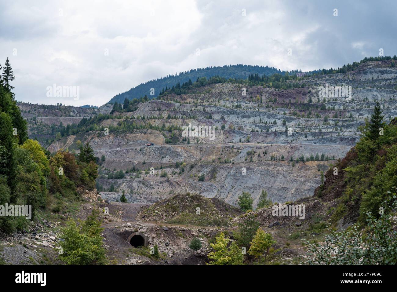 Abgestufter Tagebau in den Bergen von Vares, Bosnien 19.09.24, Vares: Symbolfoto, Illustrationsbild, Symbolbild, Illustrationsfoto, Alltagsszene Abgestufter Tagebau in den Bergen von Vares, Bosnien ein weitläufiger abgestufter Tagebau in den Bergen von Vares, Bosnien, zeigt die Spuren des Bergbaus in der Region. Die terrassenartigen Stufen des Steinbruchs durchziehen die Landschaft, während ein Tunnel und Bäume im Vordergrund zu sehen sind. Die Mischung aus industrieller Nutzung und natürlicher Vegetation prägt die Szenerie. . . Vares Hessen Bosnien-Herzegowina *** mehrstufiges Tagebau in der Stockfoto