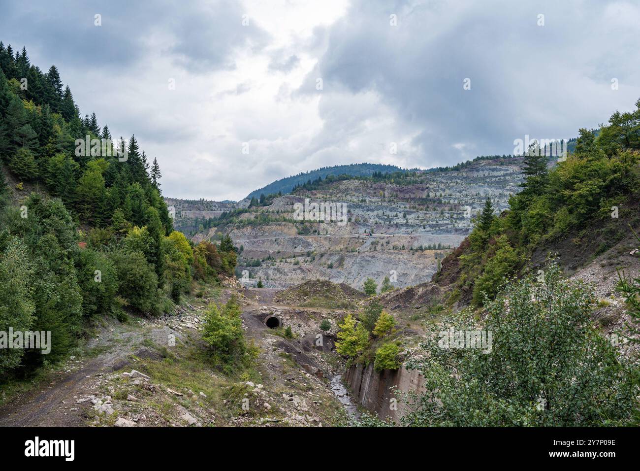 Abgestufter Tagebau in den Bergen von Vares, Bosnien 19.09.24, Vares: Symbolfoto, Illustrationsbild, Symbolbild, Illustrationsfoto, Alltagsszene Abgestufter Tagebau in den Bergen von Vares, Bosnien ein weitläufiger abgestufter Tagebau in den Bergen von Vares, Bosnien, zeigt die Spuren des Bergbaus in der Region. Die terrassenartigen Stufen des Steinbruchs durchziehen die Landschaft, während ein Tunnel und Bäume im Vordergrund zu sehen sind. Die Mischung aus industrieller Nutzung und natürlicher Vegetation prägt die Szenerie. . . Vares Hessen Bosnien-Herzegowina *** mehrstufiges Tagebau in der Stockfoto