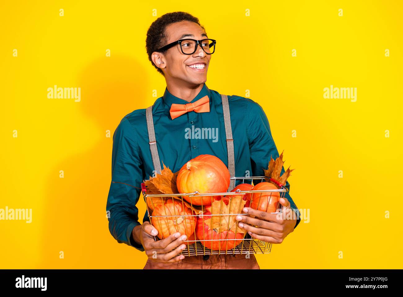 Foto-Porträt des hübschen jungen männlichen Halts Warenkorb Kürbisse aussehen leer Raum tragen trendiges Anzug Outfit isoliert auf gelbem Hintergrund Stockfoto