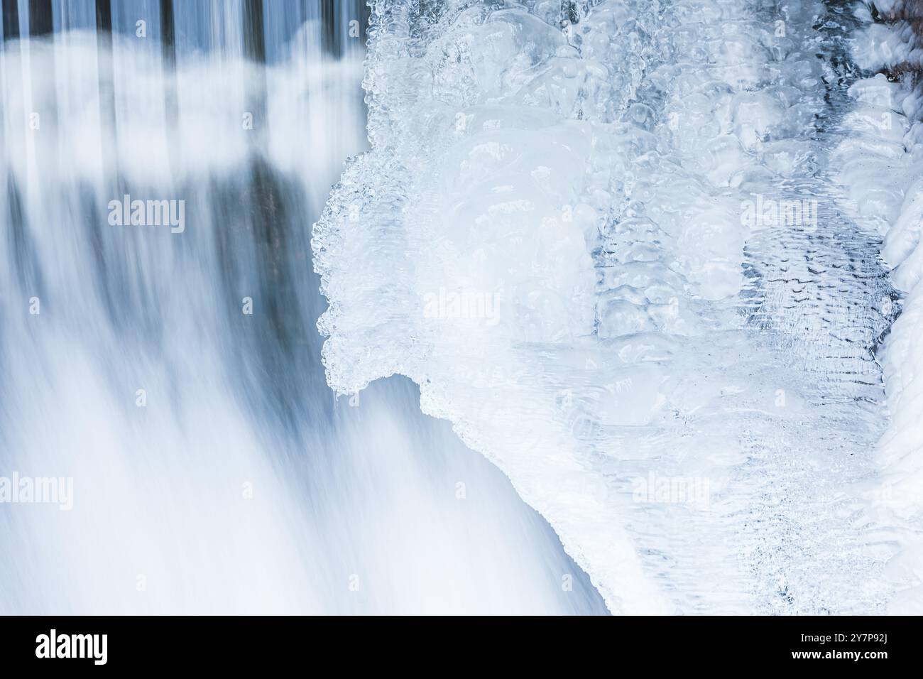 Der Wasserfall in Schweden ist von wunderschönen Eisformationen umgeben und zeigt die atemberaubende Schönheit des Winters. Der Wasserfluss steht im Gegensatz zum Stockfoto