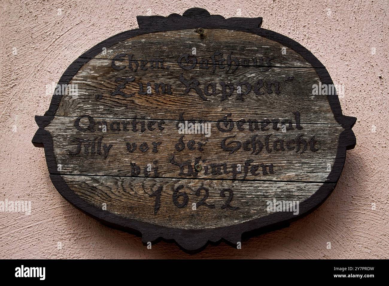 Holztafel am ehemaligen Gasthaus zum Rappen auf dem Marktplatz in Bad Wimpfen, Baden-Württemberg. Es markiert den Aufenthalt von Johann Tserclaes, Graf von Tilly, im Mai 1622, in der Nacht, in der seine Truppen und die Spanisch-kaiserlichen Truppen eine protestantische Armee in der Schlacht bei Wimpfen besiegten, einer der blutigsten Gefechte des Dreißigjährigen Krieges. Stockfoto