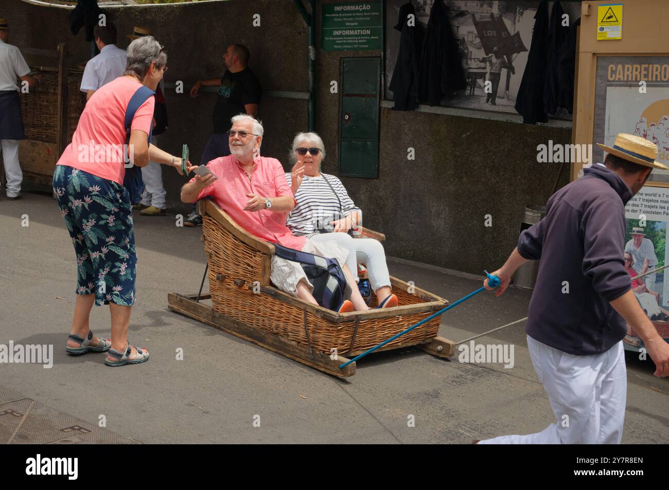 Ältere Touristen machen sich in einem Weidenschlitten niederzulassen, während ein Freund vor dem Abenteuer in der Abfahrt ihr Eigentum nimmt Stockfoto