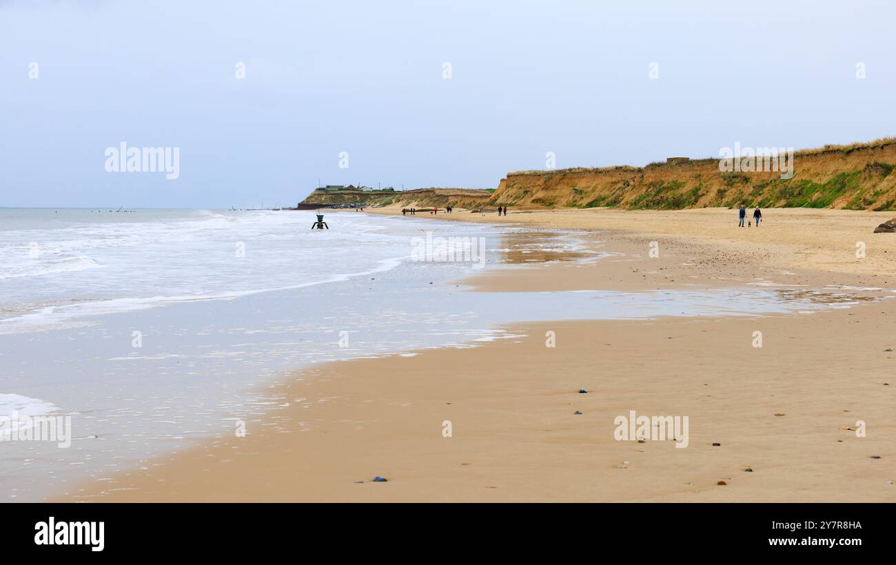 Leute, die am Strand laufen, Zeit und Tide Bell. Happisburgh, Norfolk, England. Stockfoto