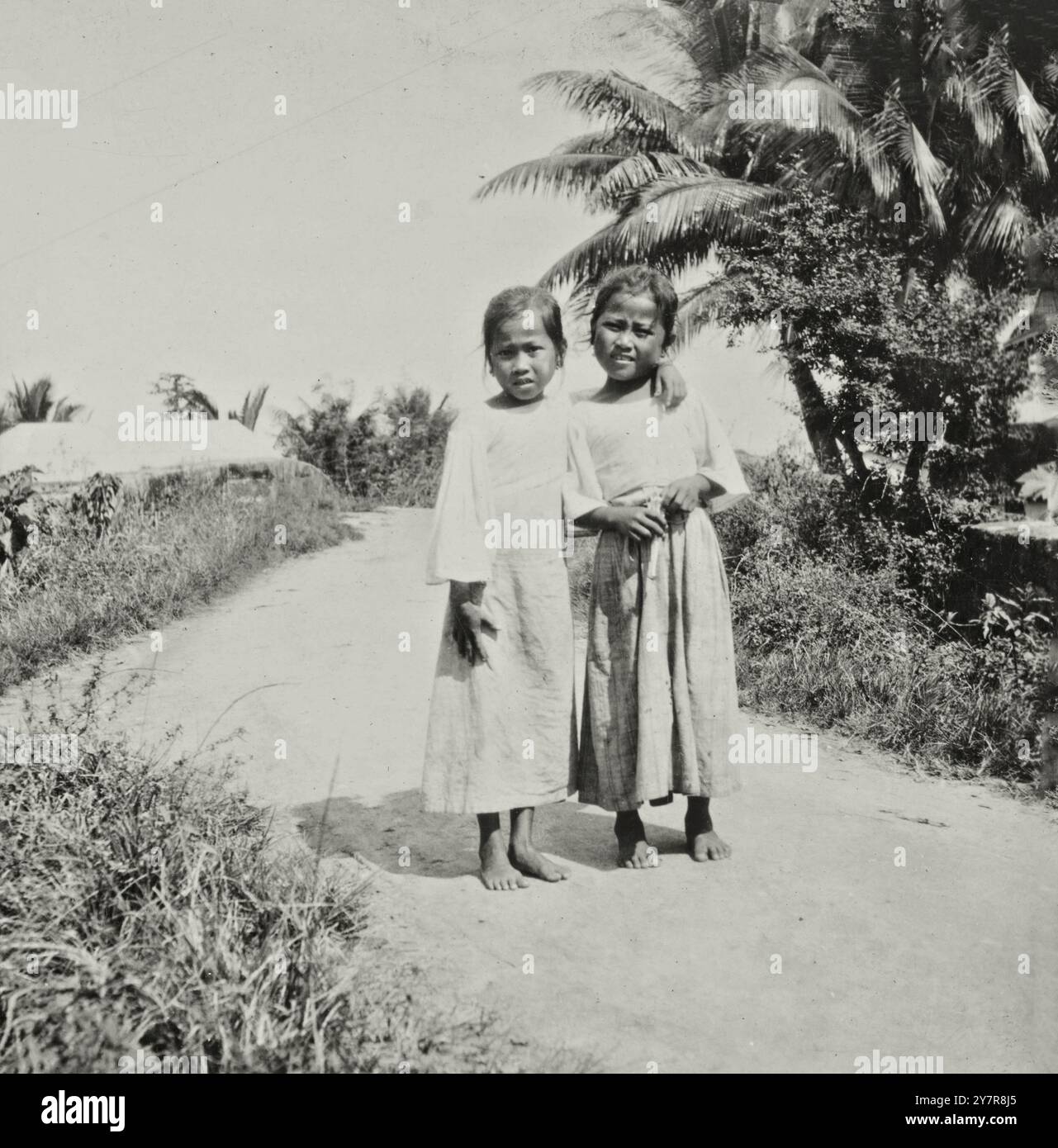 Vintage-Foto von Chamorro-Mädchen, die die Agana-Brücke überqueren, Guam. Zwischen 1890 und 1930 sind die Chamorro (auch CHamoru) die indigenen Völker der Marianen, die politisch zwischen dem US-Territorium Guam und dem umliegenden Commonwealth der Nördlichen Marianen in Mikronesien, einem commonwealth der USA, aufgeteilt sind. Stockfoto