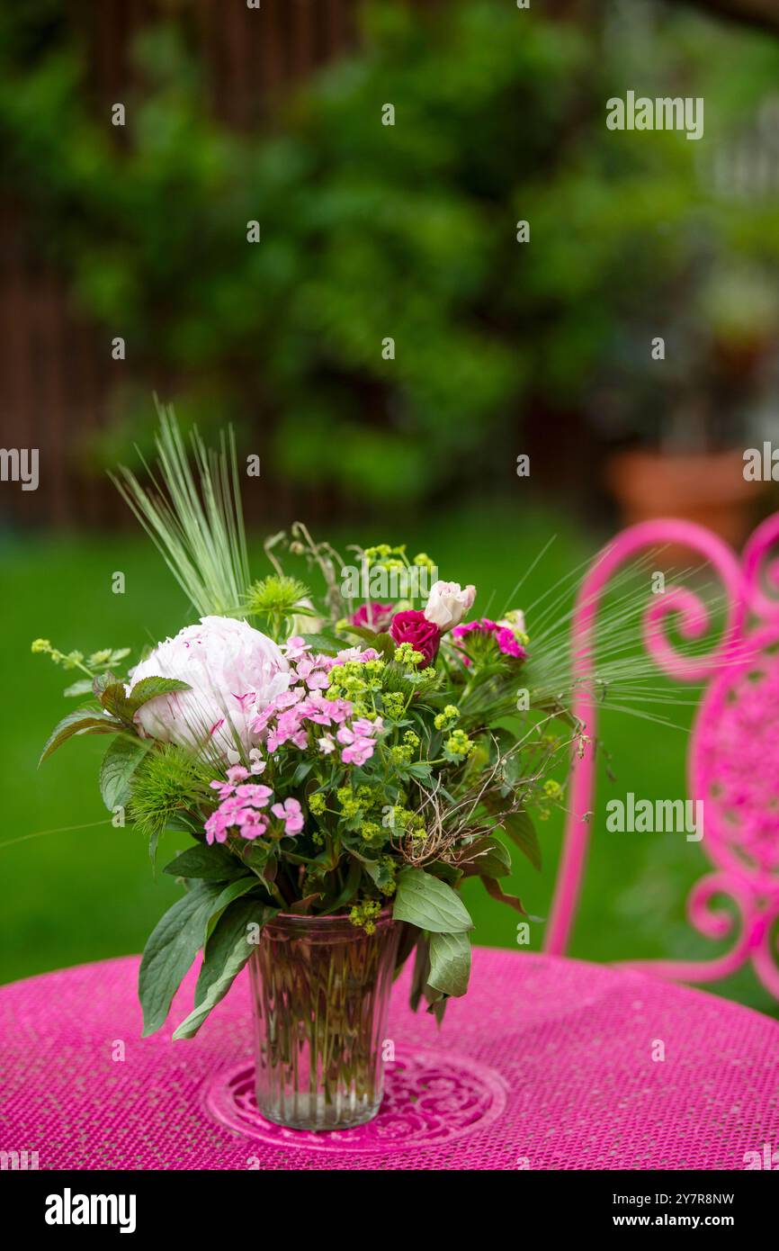 Blumenstrauß auf einem rosafarbenen Gartentisch Stockfoto