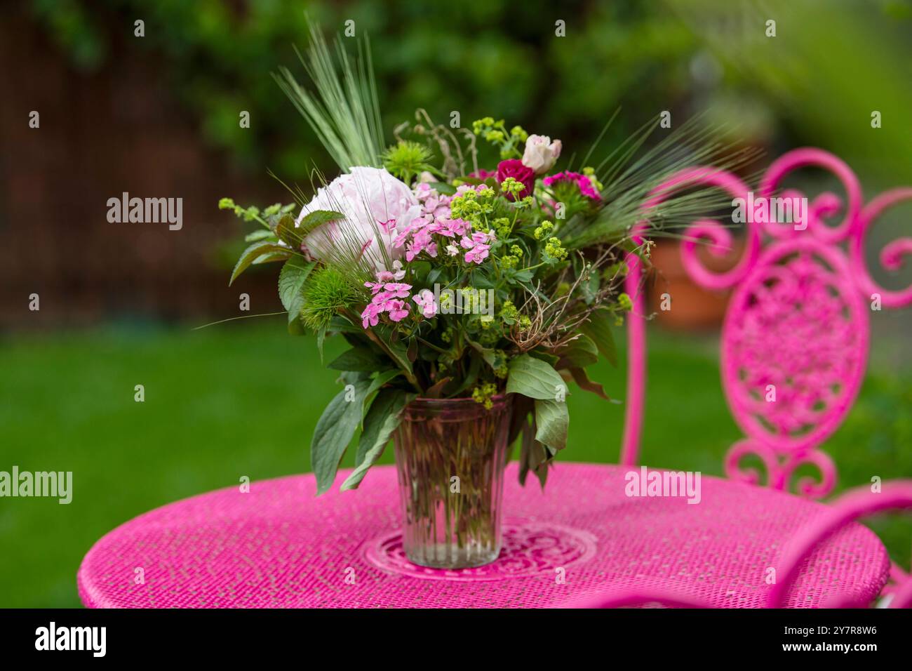 Blumenstrauß auf einem rosafarbenen Gartentisch Stockfoto
