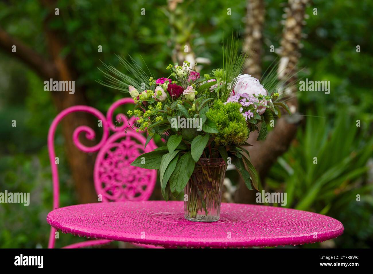 Blumenstrauß auf einem rosafarbenen Gartentisch Stockfoto
