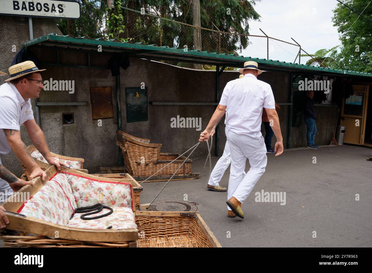 Carreiros schiebt Korbschlitten an der Rodelstation monte, mit dem Schild Babosas darüber Stockfoto
