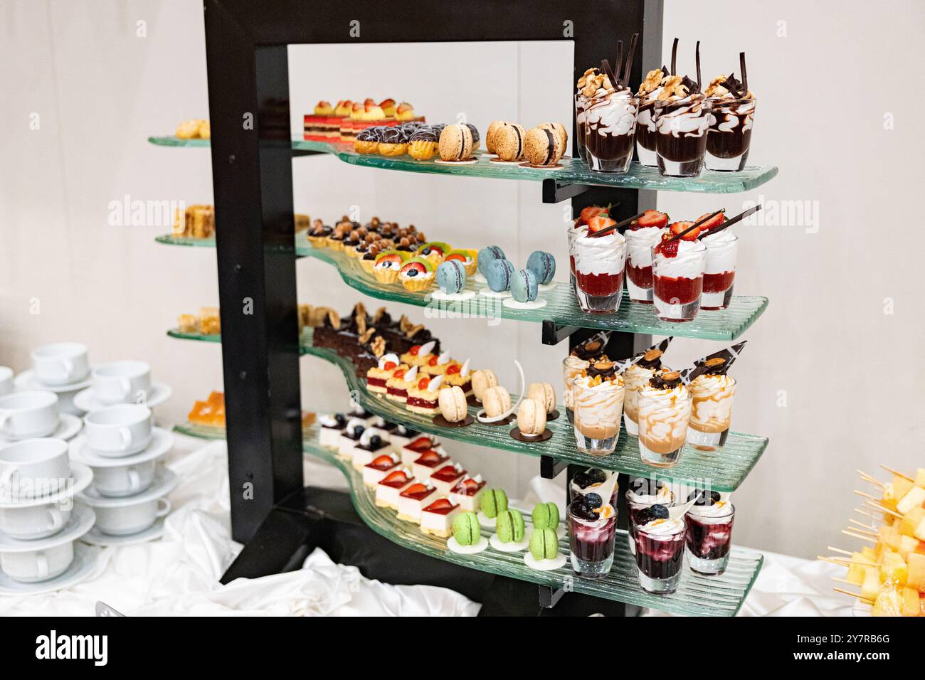 Ein Tisch voller Desserts mit einer Vielzahl von Aromen und Farben. Die Desserts werden in kleinen Plastikbechern serviert. Der Tisch ist für eine Party eingerichtet. Stockfoto