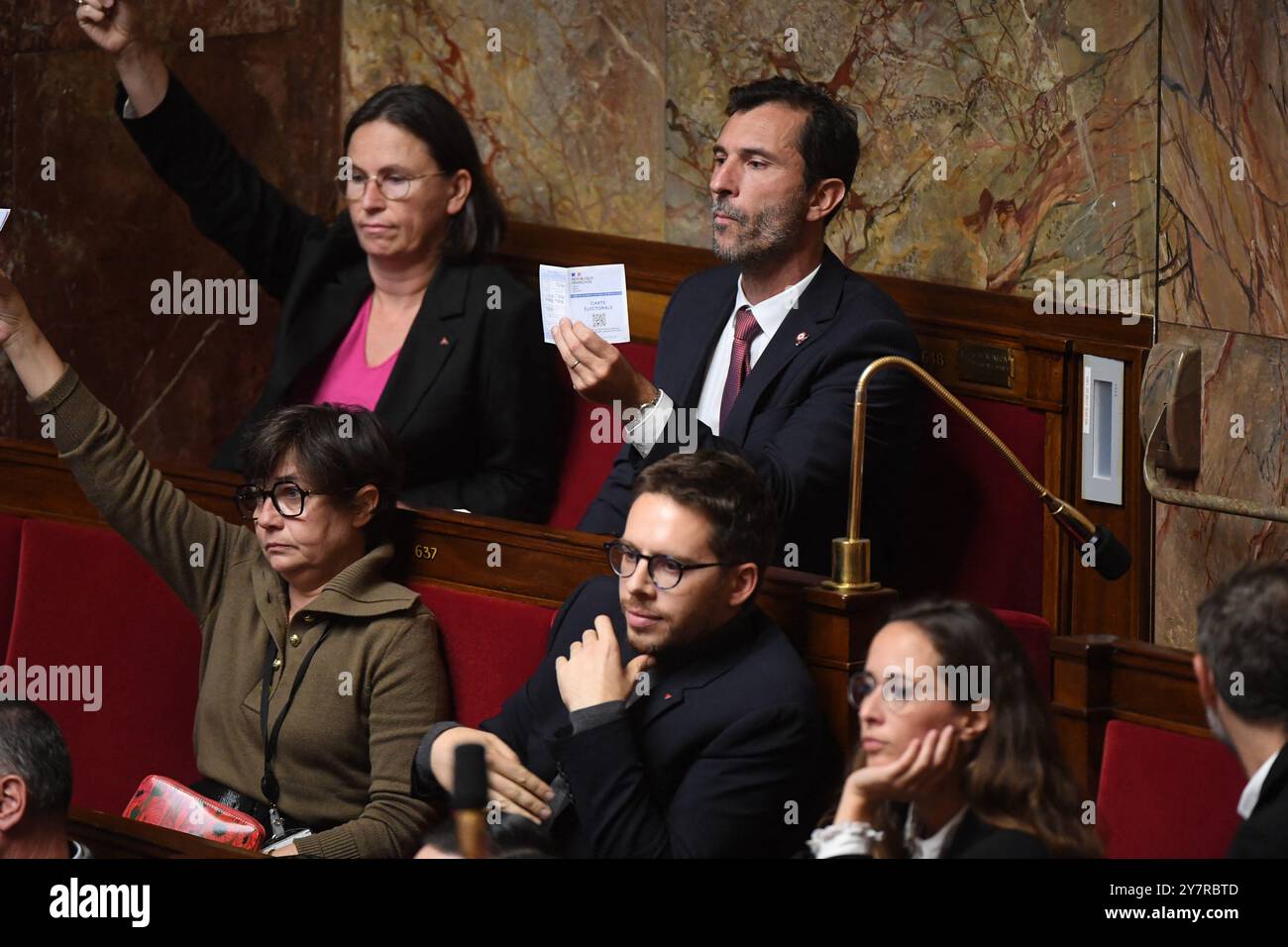 Paris, Frankreich. Oktober 2024. Die Koalitionsabgeordneten der französischen Nouveau Front Populaire (New Popular Front – NFP) halten ihre Wählerkarten, als der französische Premierminister Michel Barnier am 1. Oktober 2024 seine allgemeine politische Erklärung vor der französischen Nationalversammlung in Paris abgibt. Foto: Lionel Urman/ABACAPRESS. COM Credit: Abaca Press/Alamy Live News Stockfoto