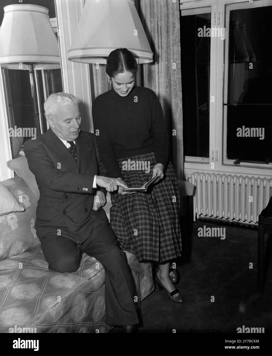 FRAU CHARLIE CHAPLIN WIRD BRITISCHER SUBJEKT 10.2,54. Mr. Und Mrs. Charles Chaplin kamen heute Nachmittag aus Genf in der Schweiz im Savoy Hotel in London an. Sie werden etwa eine Woche in London sein. Bei ihrer Ankunft in der Savoy gab Chaplin bekannt, dass seine Frau Oona nun britische Staatsbürgerin sei und diese Woche ihren britischen Pass erhalten habe. I.N.P. FOTOSHOWS - Charlie Chaplin zeigt auf den britischen Pass seiner Frau bei ihrer Ankunft im Savoy Hotel heute Abend. Bild von S. Heydinger (KOM) 359/MB/74471 International News Photo. Stockfoto