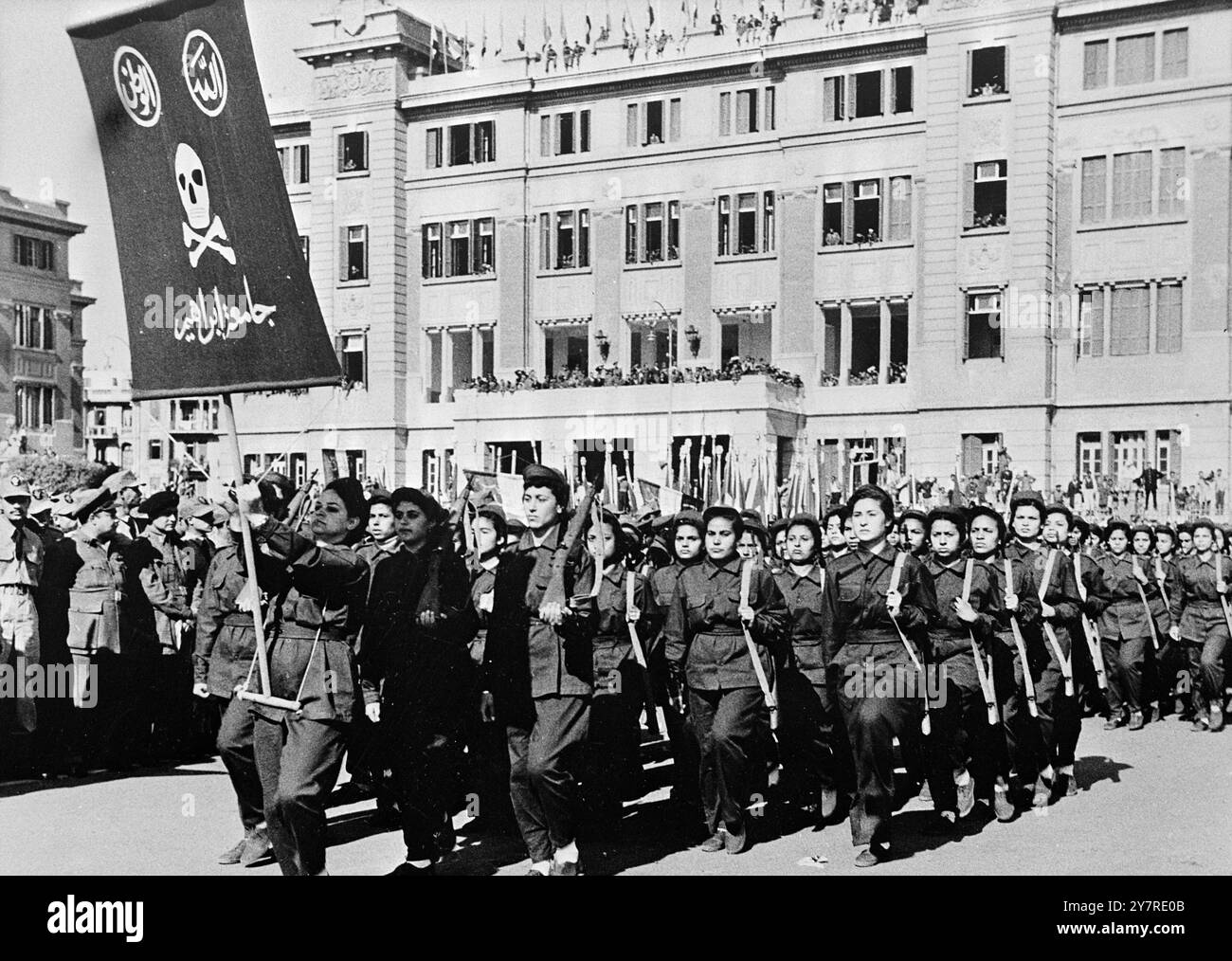 STEN GUN GIRLS MARSCHIEREN MIT SCHÄDEL- UND KREUZBEINBANNERN IN KAIRO. Am 23. Januar 1954 wurde der erste Jahrestag der ägyptischen Befreiung gefeiert. In Kairo veranstaltete der ägyptische Präsident General Neguib seine bisher größte Parade mit 35.000 Freiwilligen der Miliz. Hervorzuheben waren 300 Sten Gun Girls, gekleidet in olivgrünen Schlachtkleidern. General Neguib nahm den Gruß von einem eigens errichteten Stand auf dem Republikanischen Platz, der mit einem riesigen rot-weißen Schädel und gekreuzten Knochen bedeckt war. I.N.P. FOTOSHOWS. Ein Kontingent der Sten-Pistole-Mädchen, gefolgt von einem Schädel- und Kreuzknochenbanner, marschiert in der Parade Stockfoto
