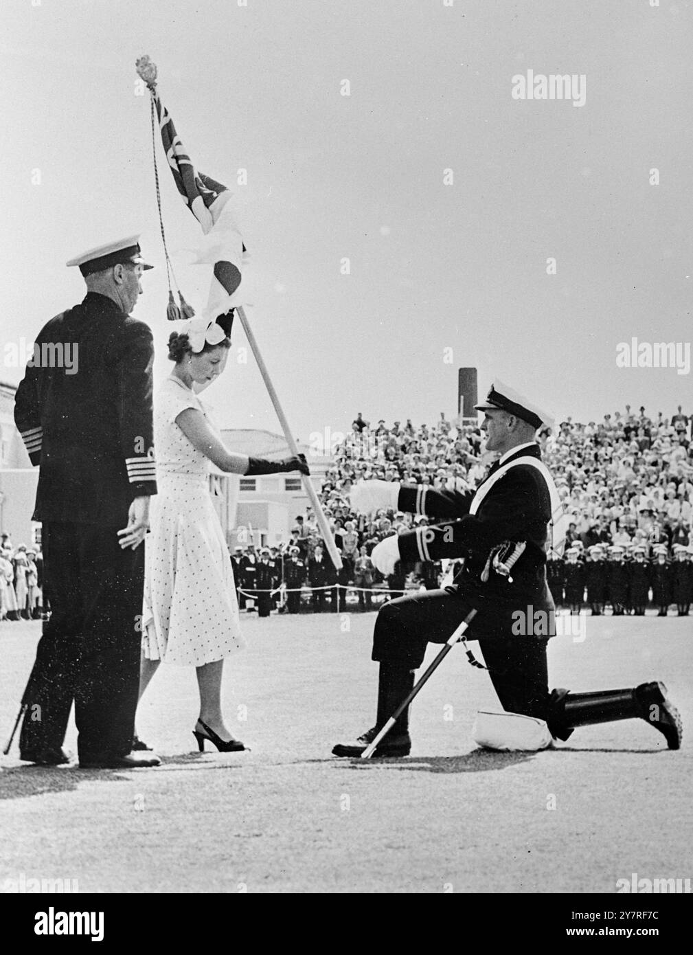 Bild per Funkgerät. Queen präsentiert ihre Farben in Neuseeland. Sun kommt zur großen Parade raus. 24.12.53. Auckland. Die Königin trägt einen Rock aus cremiger Seide mit kleinen schwarzen Flecken und präsentiert ihre Farben ihrer neuseeländischen Marine in einer Zeremonie im Devonport Dockyard, Auckland. Lieutenant Joe Quinn, der bei der Queen's Krönung in London mit der berittenen Eskorte der Königin ritt, hielt die Fassung, in die der Standard von Ihrer Majestät gesetzt wurde. Tausende sahen die Parade bei strahlendem Sonnenschein. H. 7346I. (PL) herausgegeben von Press Photo Combine. Stockfoto