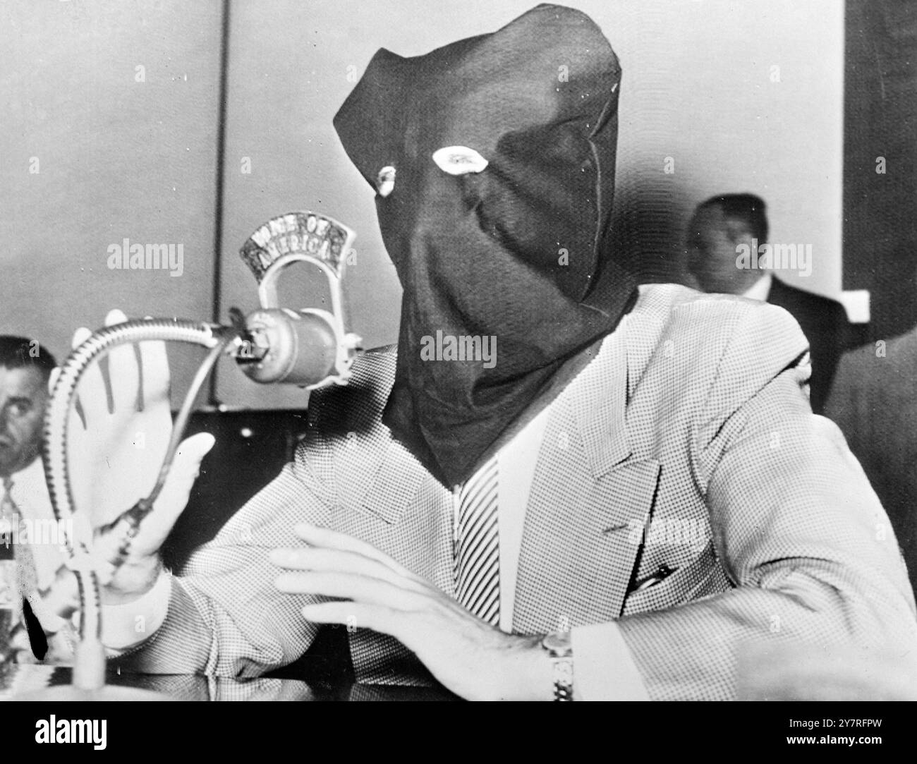 Ein Zeuge mit Kapuze erzählt von einem russischen Massaker. Am 12. Oktober 1953 sagte ein Mann mit Kapuze bei einer Anhörung in Detroit aus, die diese Woche vor dem Unterausschuss für Ermittlungen des US-Repräsentantenhauses die sowjetische Besetzung der Balkanländer untersucht hatte. Der Mann, der vermummt war, um eine Identifizierung und mögliche Repressalien gegen Verwandte in den besetzten Ländern zu verhindern, weinte, als er sagte, dass 500 litauische Männer, Frauen und Kinder im Juni 1941 von russischen Soldaten im Camp Praviemiskis massakriert wurden. Ein I.N.P.-Foto zeigt, wie der Zeuge über das angebliche Massaker spricht. Fotos Von Internationalen Nachrichten. . Stockfoto