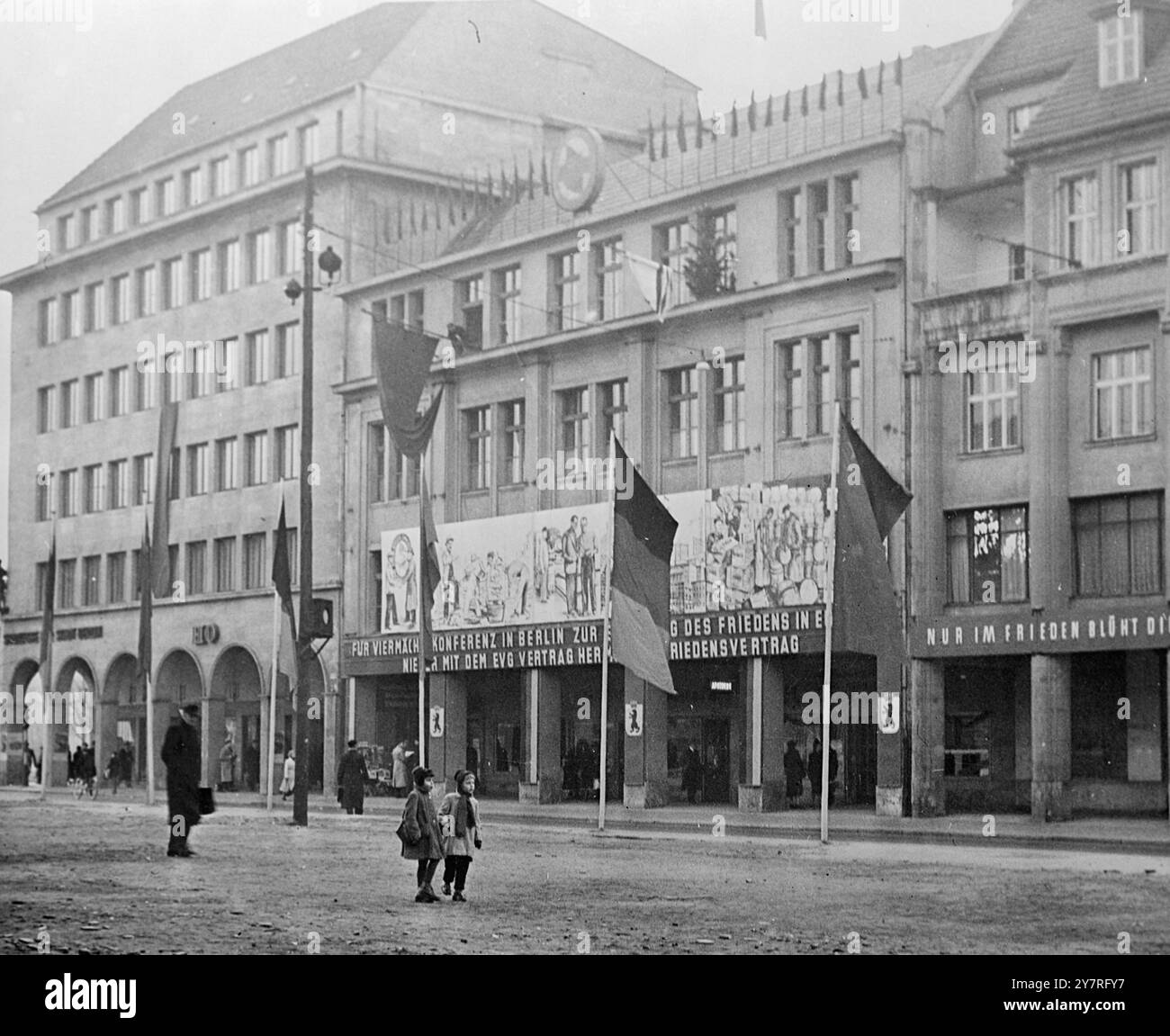 Ostdeutschland ruft zu Big-Four-Treffen 5.12.53 auf. Nein, die DDR hat sich dem kommunistischen Chor für eine vier-Mächte-Konferenz angeschlossen. Auf den Büros der Kommunistischen Partei in Ost-Berlin ist ein großes Poster mit friedlicher Arbeit und Wiederaufbau mit einem Text in deutscher Sprache zu lesen: "Für vier-Mächte-Konferenzen in Berlin zur Wiederherstellung des Friedens in Europa. Mit der Ratifizierung des EDC, grüße einen Friedensvertrag." 251/PJ/73099 International News Photos. Stockfoto