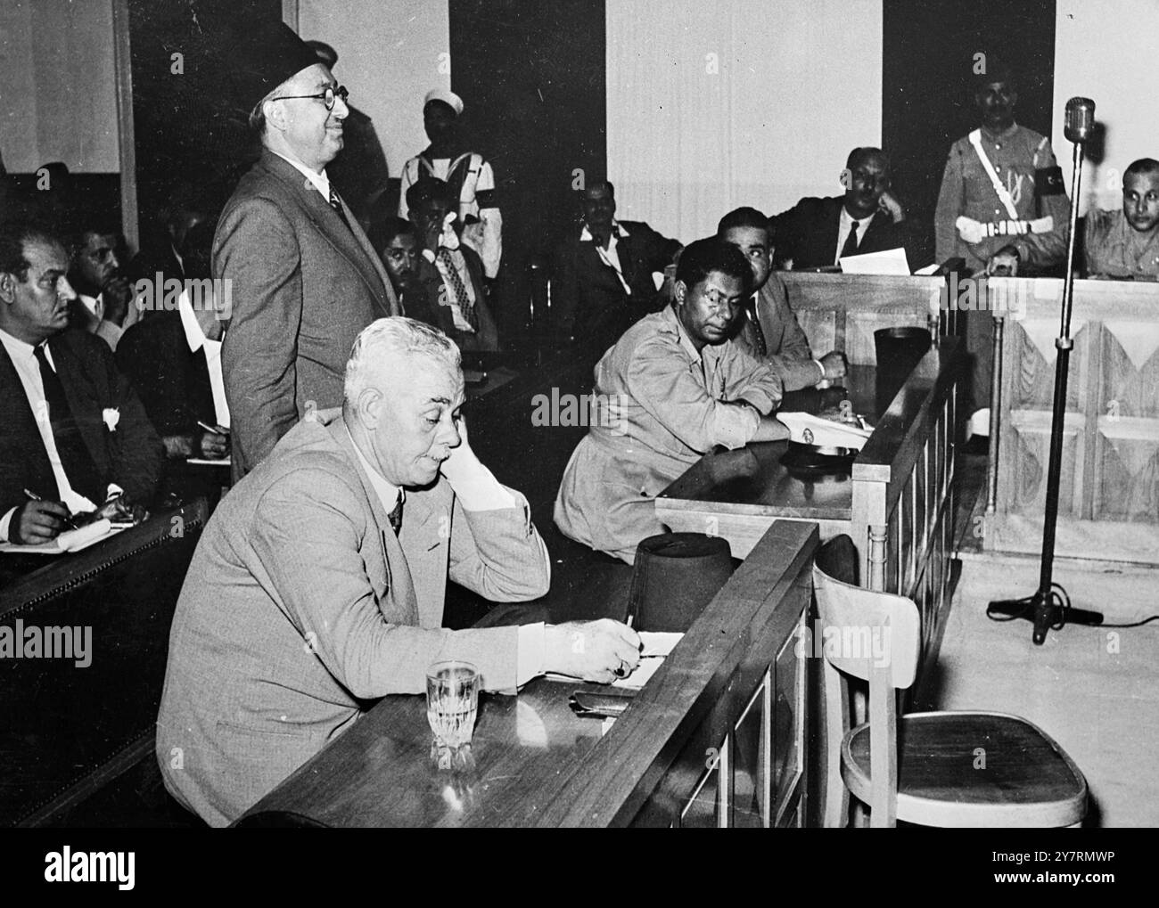 KAIROER TODESURTEIL GEGEN DEN EHEMALIGEN PREMIER. 2.10.53. Gestern wurde Abdel Hadi, der 57 Jahre alt und ehemaliger ägyptischer Premierminister war, vom neu gegründeten Revolutionsgericht in Kairo zum Tode durch Erhängen verurteilt. Er wurde des Verrats, der Korruption und des Machtmissbrauchs beschuldigt. Das Gericht ordnete auch die Einziehung seines Vermögens an. Abdel Hadi, groß und silberhaarig, hörte unbeirrt zu, wie die Todesstrafe von Wing Commander ausgesprochen wurde. Boghdadi, Kriegsminister, Präsident des Tribunals. I.N.P. FOTO ZEIGT: Der Zeuge Housain Rasfat gibt seine Aussage, während der Angeklagte Abdel Hadi sitzt und zuhört Stockfoto