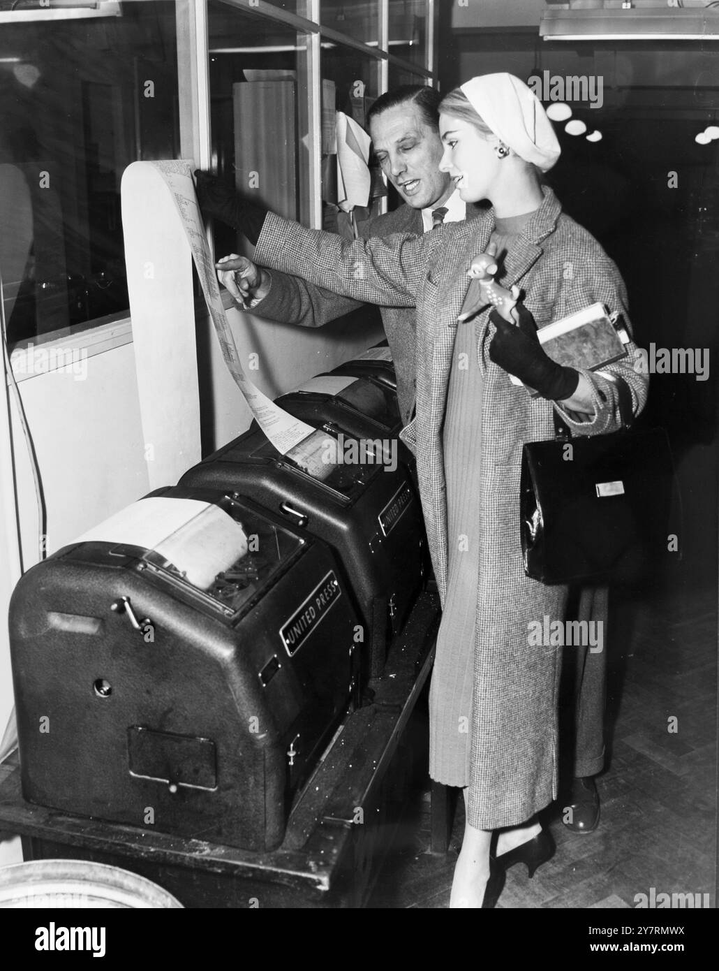 Miss World in den Nachrichten - kürzlich zur Miss World gewählt, Miss Finland, Marita Lindhahl, 18, besuchte den Nachrichtenraum von United Press International in der Fleet Street, London. Um herauszufinden, wie die Nachricht, dass sie den Titel von Miss World gewann, so schnell zu ihr nach Hause kam, und hier, um den Prozess des Versendens eines Telfotos zu erklären, ist Henry Parker, Telephoto Engineer - 17. Oktober 1957 Stockfoto