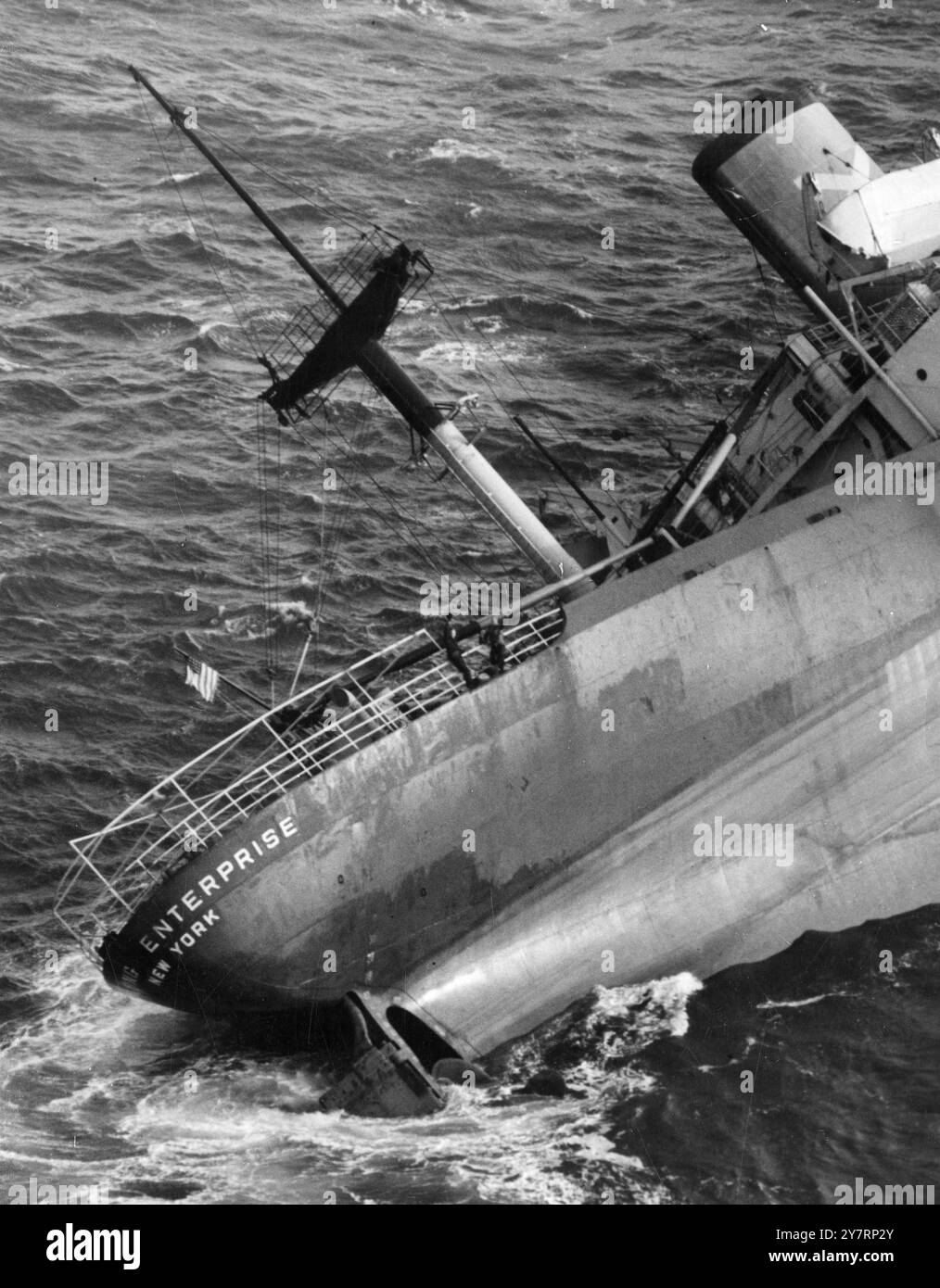 Im Atlantik: Über die Schienen auf dem Heck des betroffenen amerikanischen Frachters Flying Enterprise schweben Captain Kurt Carlsen und Mate Dancy vom britischen Schlepper Turbulenzen zu dem Flugzeug, von dem dieses Bild aufgenommen wurde. Das Schiff wird jetzt von den Turbulenzen nach Falmouth, Cornwall, gezogen, wo ein toller Empfang für den galanten Captain geplant wurde. 8. Januar 1952. FOTOS VON HERBERT ANDREWS, DIE VON EINEM SPEZIELLEN GECHARTERTEN FLUGZEUG STAMMEN Stockfoto