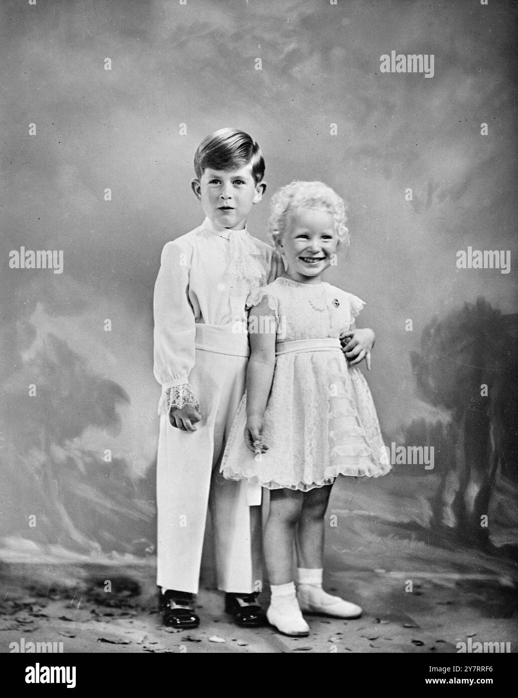 PRINZESSIN ANNE's DRITTER GEBURTSTAG H.R.H. Prinzessin Anne ist drei Jahre alt am Samstag, 15. August 1953. Das I.N.P.-Foto zeigt Ein Porträt der Prinzessin mit ihrem Bruder Prinz Charles, aufgenommen von Marcus Adams anlässlich ihres Geburtstags. Die königlichen Kinder tragen die Kleider, die sie am Krönungstag trugen. Prinzessin Annes Kleid besteht aus cremefarbener französischer Spitze über Chiffon und Taft. Die Kette aus acht echten Perlen an einer Platin-Kette gehört der Königin. Die Brosche, ein Kreis aus Rubinen und Diamanten, wurde der Königin als Kind von Königin Mary gegeben. Prinz Charles trägt Creme serge To Stockfoto