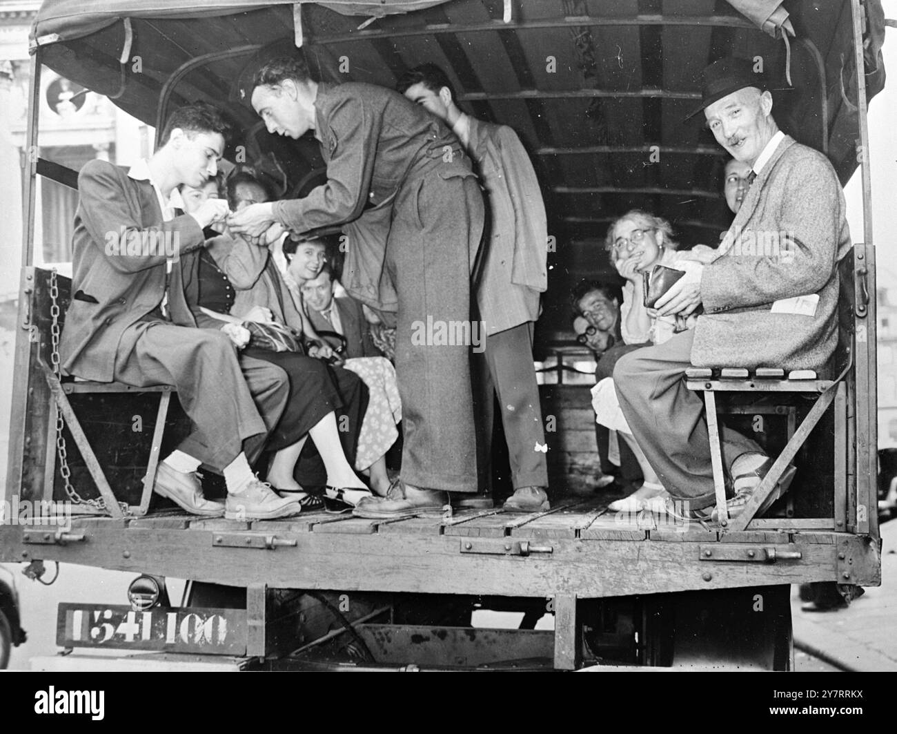 MILITÄRBUSDIENST IN PARIS 13.8.53Französische Truppen, Männer des 121. Verkehrsregts, wurden gestern nach Paris gebracht, um einen "Bus"-Dienst anzubieten, als ein 24-Stunden-Streik von Beschäftigten des öffentlichen Nahverkehrs ausgerufen wurde. 17 Routen werden von Heereswagen zu einem Pauschalpreis von 30 Franken abgedeckt. Das Foto zeigt Einen Soldaten, der als Dirigent auf einem der LKW fungiert, der als Bus genutzt wird, und sammelt die 30 Francs Fahrpreis von fröhlichen Pariser, die zur Arbeit reisen. August 1953 Stockfoto