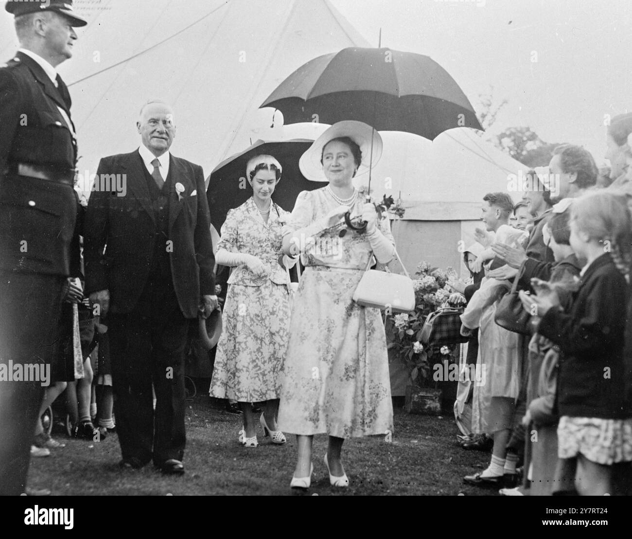 KÖNIGLICHES LÄCHELN IM REGEN BEI DER SANDRINGHAM FLOWER SHOW 31.7,53. Königin Elizabeth, die Königin Mutter und H.R.H. Prinzessin Margaret nahmen am Mittwoch an der Sandringham Flower Show Teil. Unbeeindruckt vom Regen spazieren die Königin Mutter und Prinzessin lächelnd durch die Show, begleitet von Mr. C. H. Cook, dem Vorsitzenden. 31. Juli 1953 Stockfoto