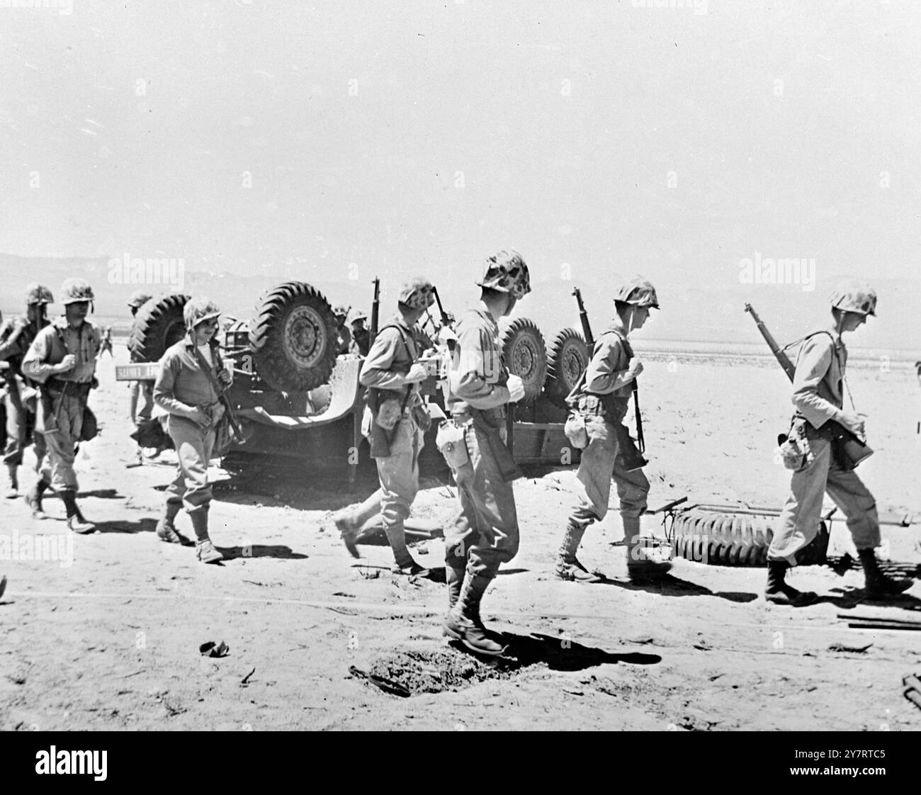 Ein umgekippter Truck wird von Marines überfahren, als sie den Vorwärtsstoß nach dem Atomtest untersuchten, der vor kurzem auf dem AEC Nevada Proving Grounds, Nevada, USA24 April 1952 stattfand Stockfoto